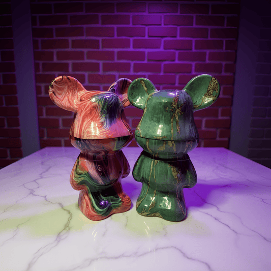 Bear Sculpture Herb GrinderTwo colorful ceramic herb grinder with mouse ears on a marble surface against a brick wall.