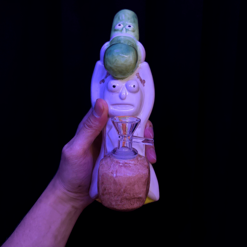 Glass pipe with character design held by a hand against a black background