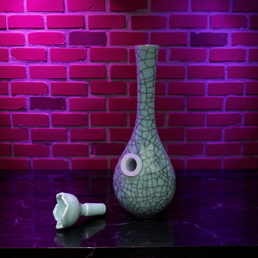 Crackle Glaze Slim Neck Celadon Porcelain Bonga green ceramic bong and a ceramic bowl is placed on a textured surface