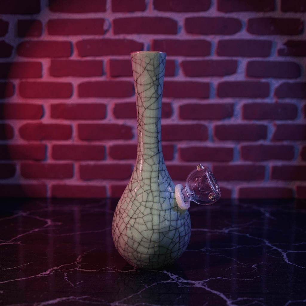 Crackle Glaze Slim Neck Celadon Porcelain Bonga slim neck crackle celadon porcelain bong with glass bowl is placed on a wooden surface.