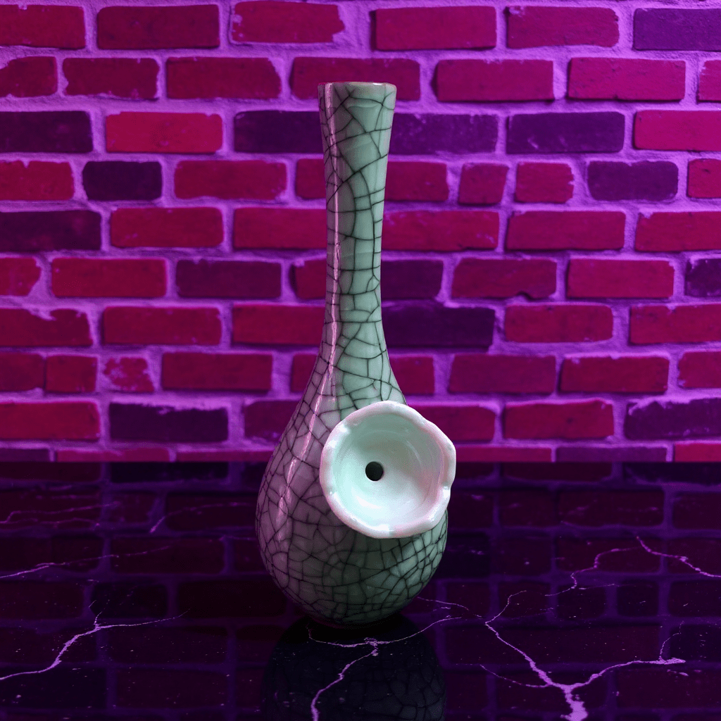Crackle Glaze Slim Neck Celadon Porcelain BongGreen ceramic bong with a textured surface against a brick wall.
