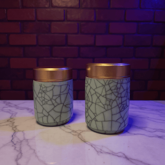 Crackled Blue - Green Celadon Porcelain Stash JarTwo crackled blue celadon porcelain stash jars with gold lids on a marble