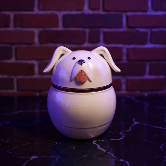 Cute Ceramic Dog Herb Grinder - White dog - shaped ceramic herb grinder with a red nose on a dark surface