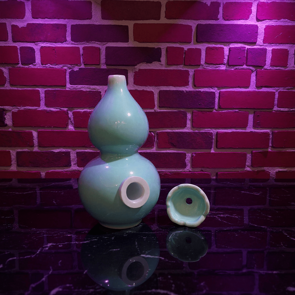 Glossy Blue Celadon Gourd Porcelain BongGlossy Blue Celadon Gourd Porcelain Bong and ceramic bowl are placed on a wooden surface.