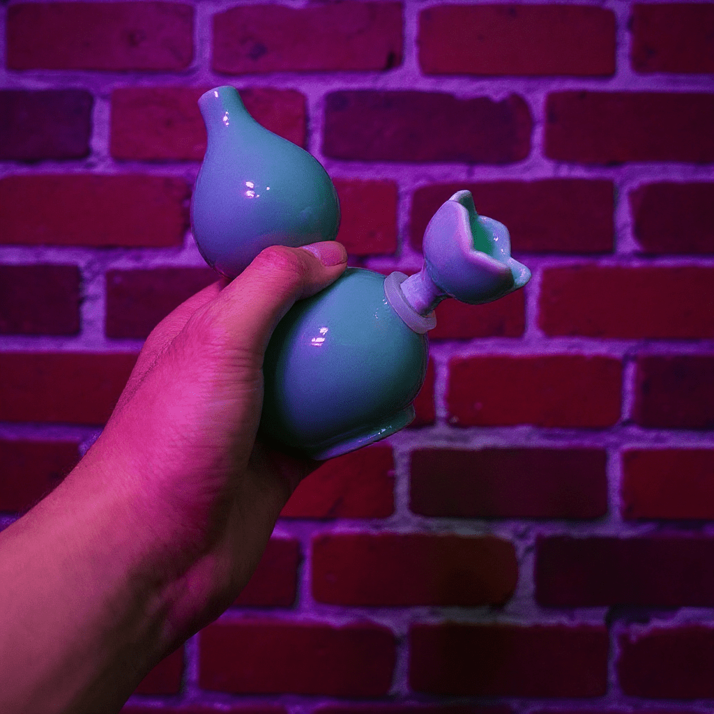 Glossy Blue Celadon Gourd Porcelain BongHand holding a green porcelain against a brick wall with purple lighting