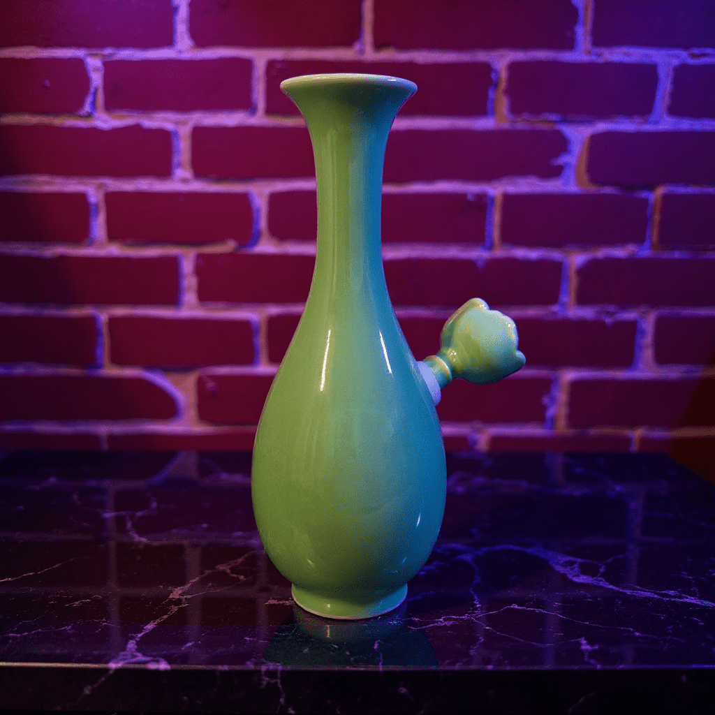 Glossy Green Celadon Bong with Flared TopFlared Neck Glossy Green Celadon Porcelain Bong with ceramic bowl is placed on a marble surface.