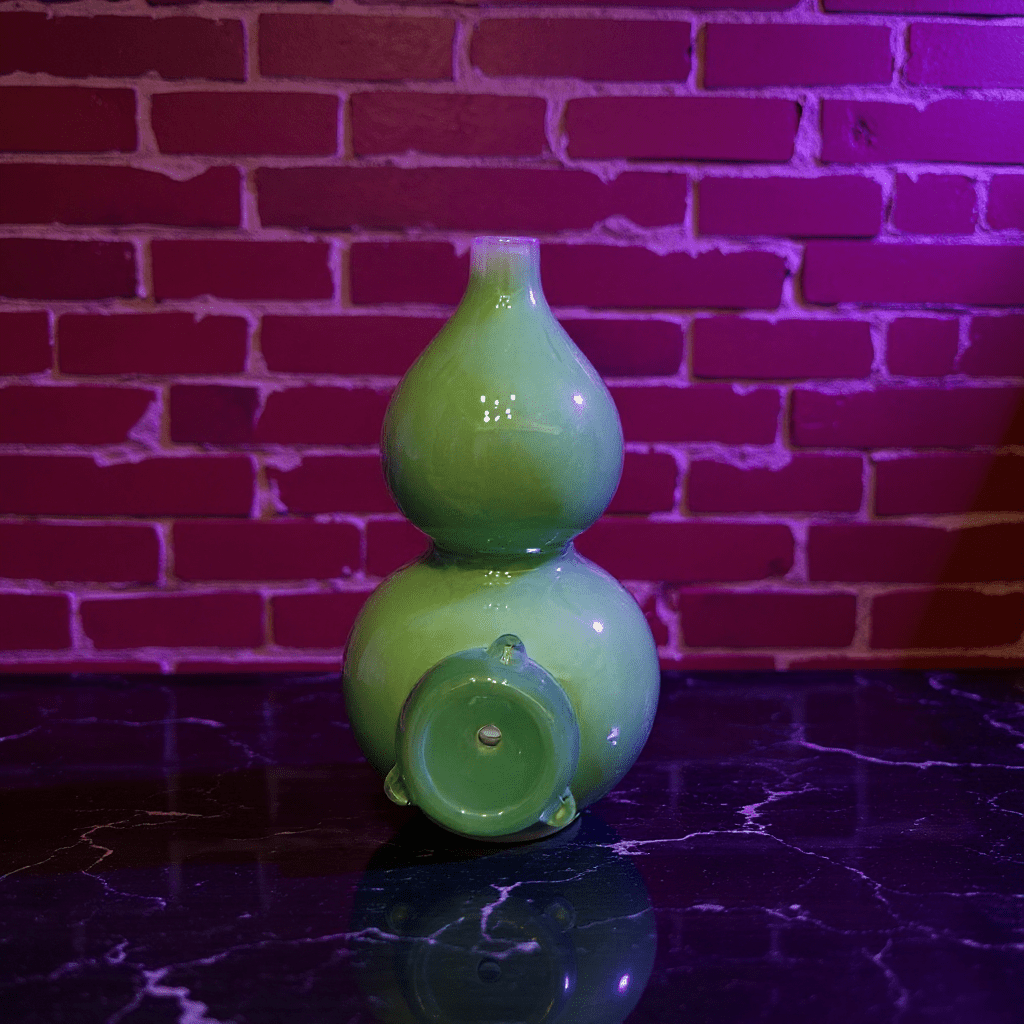 Glossy Green Celadon Gourd Porcelain BongGreen ceramic bong with glass bong on a reflective surface