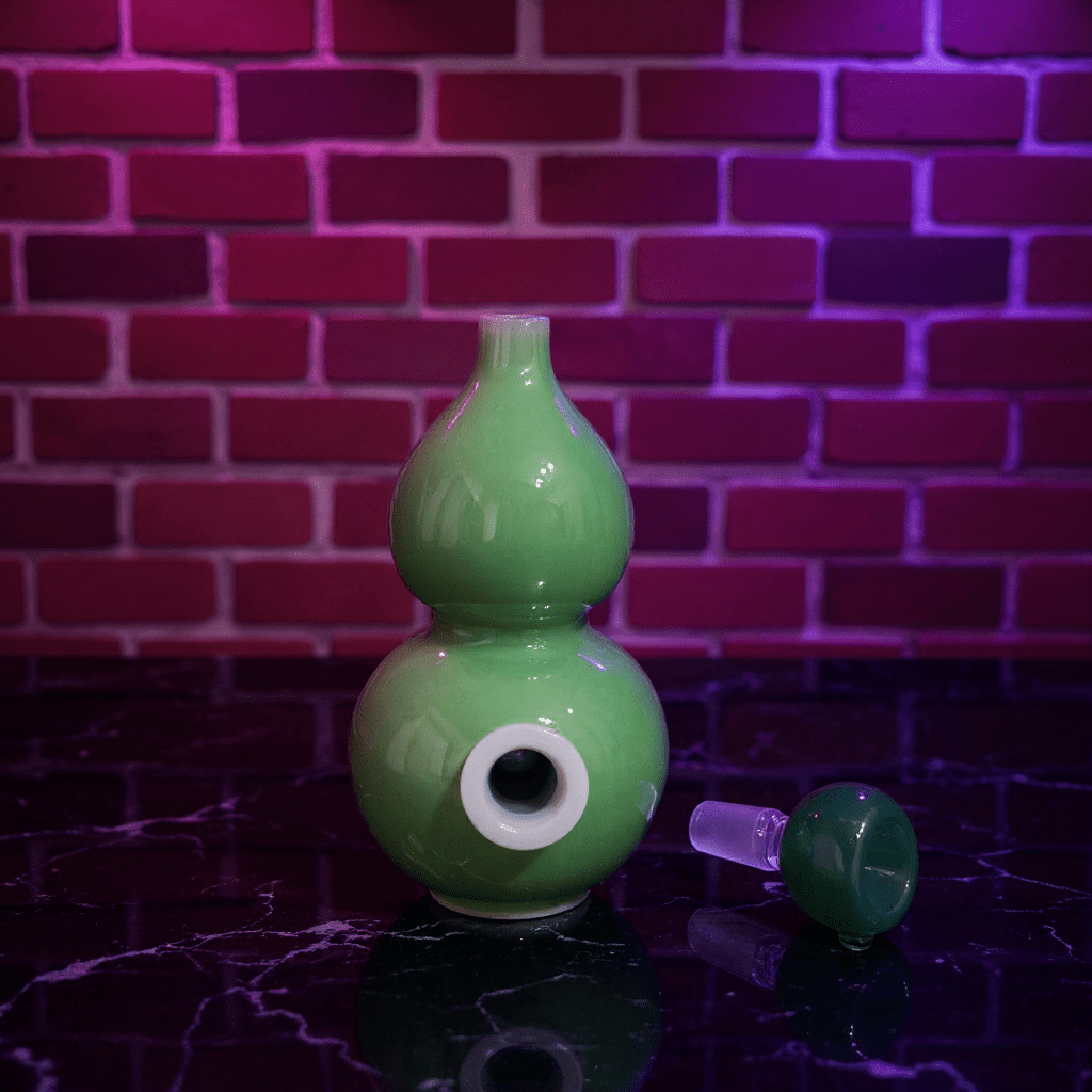 Glossy Green Celadon Gourd Porcelain BongGlossy Green Celadon Gourd Porcelain Bong and glass bowl are placed on a marble surface.