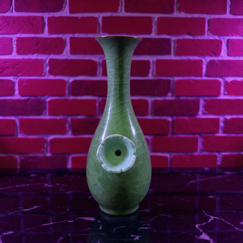Green Ice - Crack Celadon Porcelain Bong with Flared TopGreen ceramic bong against a red brick wall