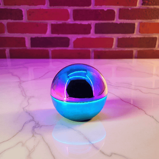 Holographic Ball Herb Grinder Multicolored spherical grinder on a marble surface with a brick wall background