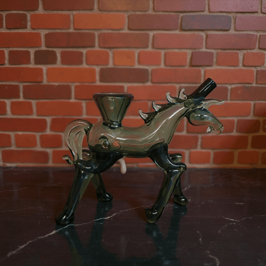 Horse Glass Hand Pipe - Decorative glass horse hand pipe on a dark surface with a brick wall background