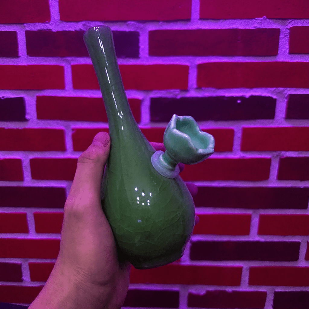 Ice - Crack Celadon Bong with Slim Neck DesignGreen ceramic bong held against a red brick wall