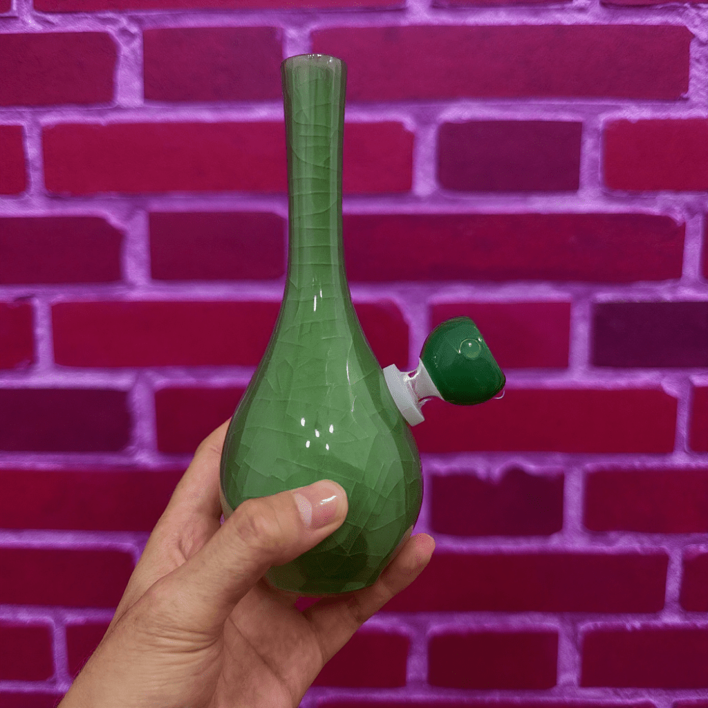 Ice - Crack Celadon Bong with Slim Neck DesignGreen glass pipe held in front of a red brick wall