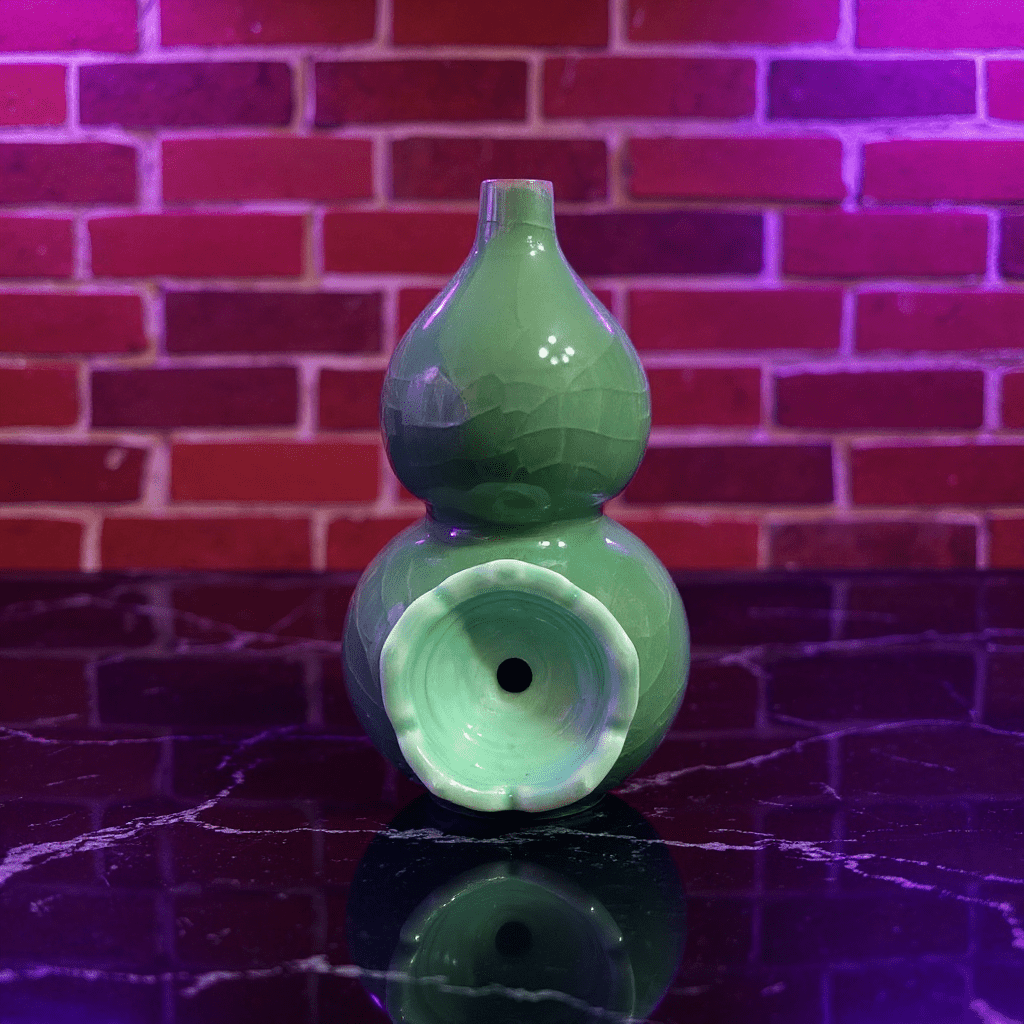 Ice - Crack Green Celadon Gourd Porcelain BongGreen ceramic gourd - shaped bong on a reflective surface with a brick wall background