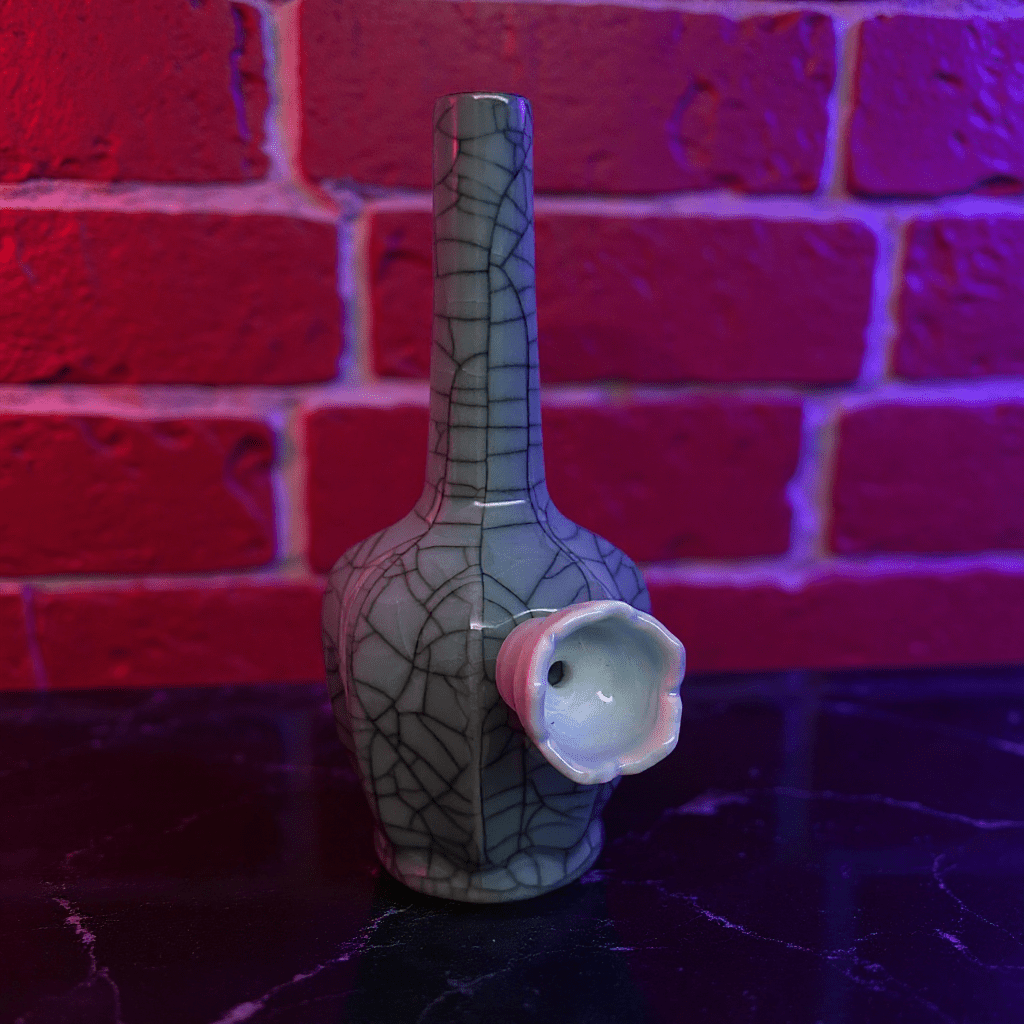 Ice - Crack Light Blue Celadon Flat - Sided Porcelain BongDecorative ceramic bong with unique design against a brick wall background