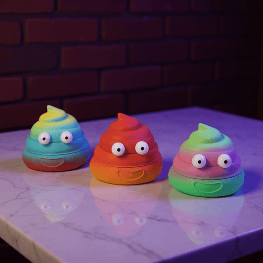 poop emoji shaped grinder - Sh*t Face Herb Grinderpoop emoji shaped grinder - three colorful poop grinders—blue, red, and green—lined up on a dark tabletop.