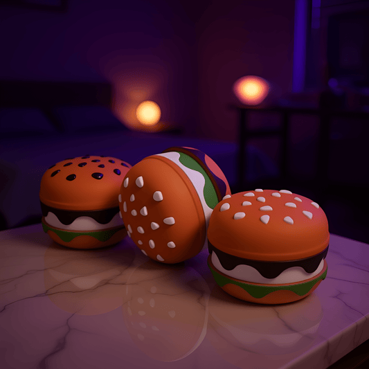 Stacked Burger Herb Grinder - Three burger herb grinders with different sesame seed styles displayed on a purple bedspread.