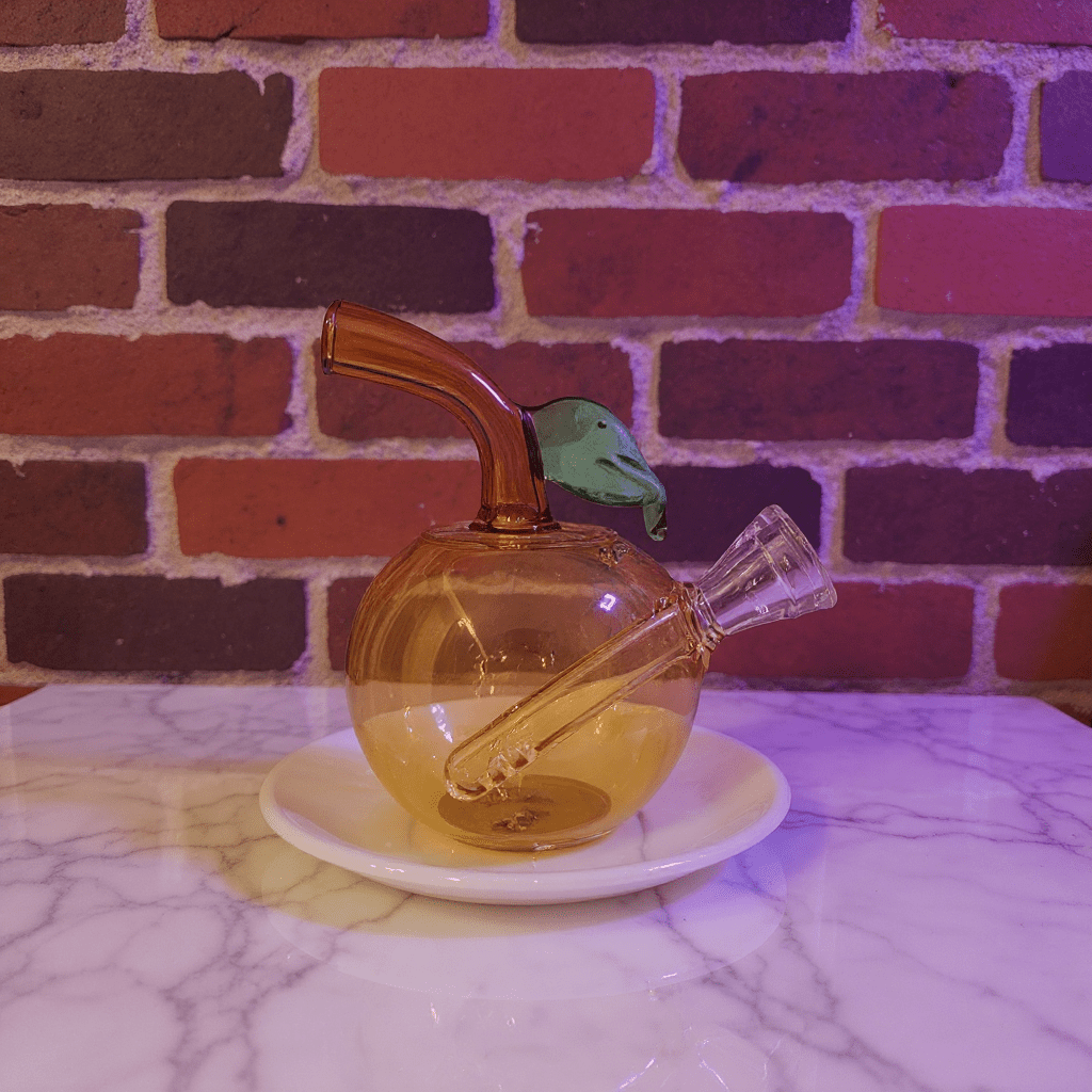 🍎 Apple Glass Bong – Mini Fruit Water PipeBrown glass smoking bong with a bird - shaped piece on a marble surface