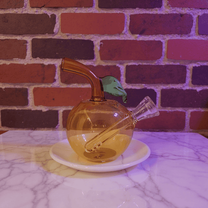 🍎 Apple Glass Bong – Mini Fruit Water PipeBrown glass smoking bong with a bird - shaped piece on a marble surface