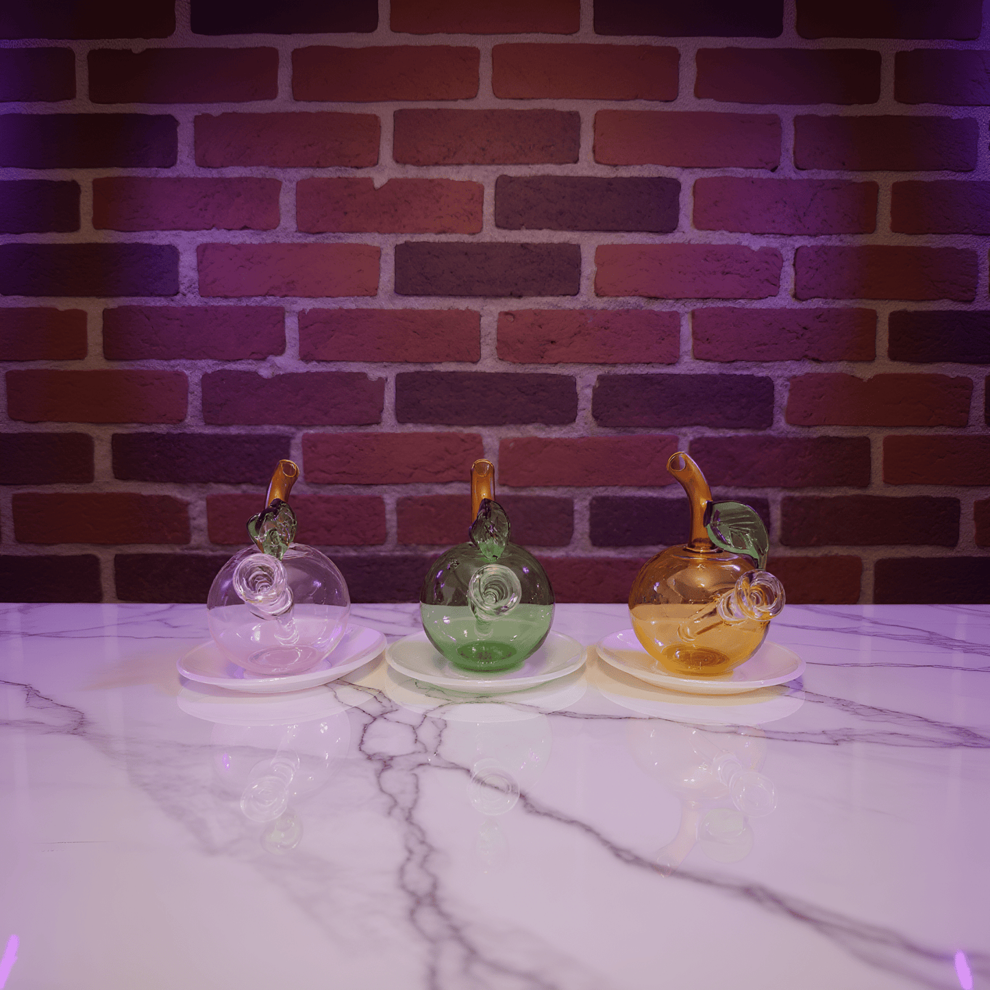 🍎 Apple Glass Bong – Mini Fruit Water PipeThree colorful glass bong on a marble surface with a brick wall background