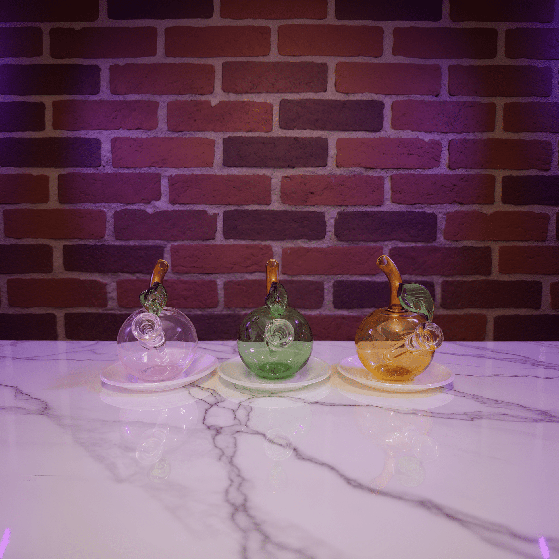 🍎 Apple Glass Bong – Mini Fruit Water PipeThree colorful glass bong on a marble surface with a brick wall background