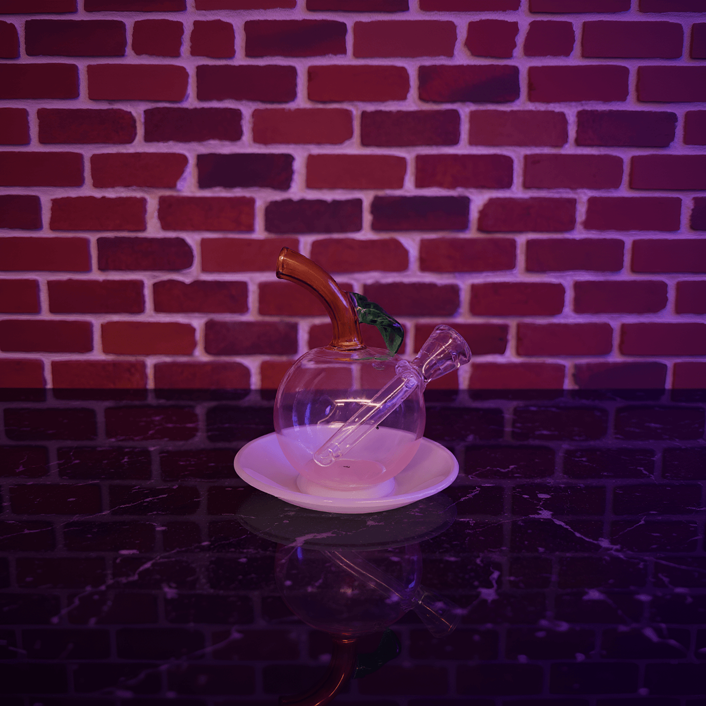 🍎 Apple Glass Bong – Mini Fruit Water PipeGlass smoking bong with a metallic accent on a white plate