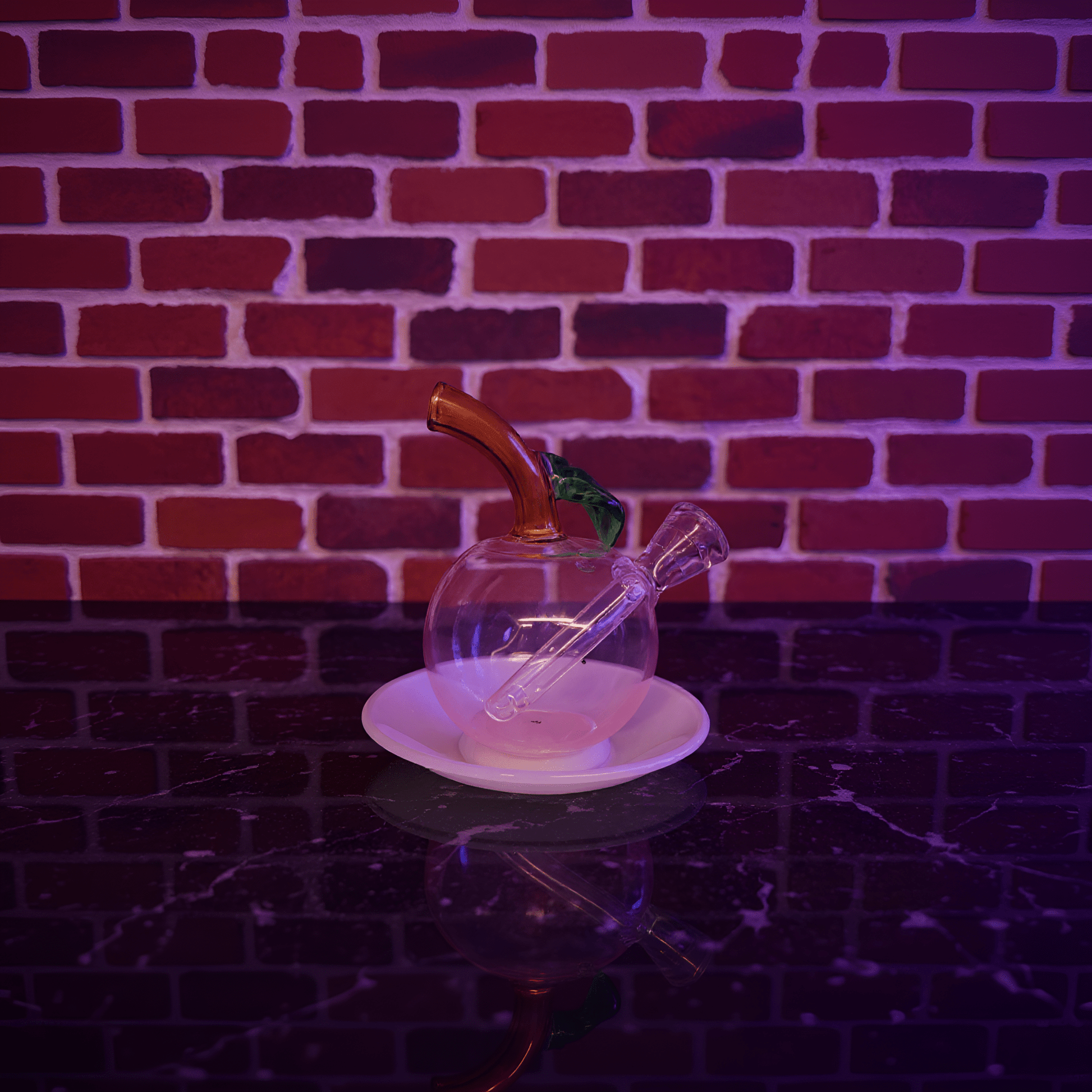 🍎 Apple Glass Bong – Mini Fruit Water PipeGlass smoking bong with a metallic accent on a white plate