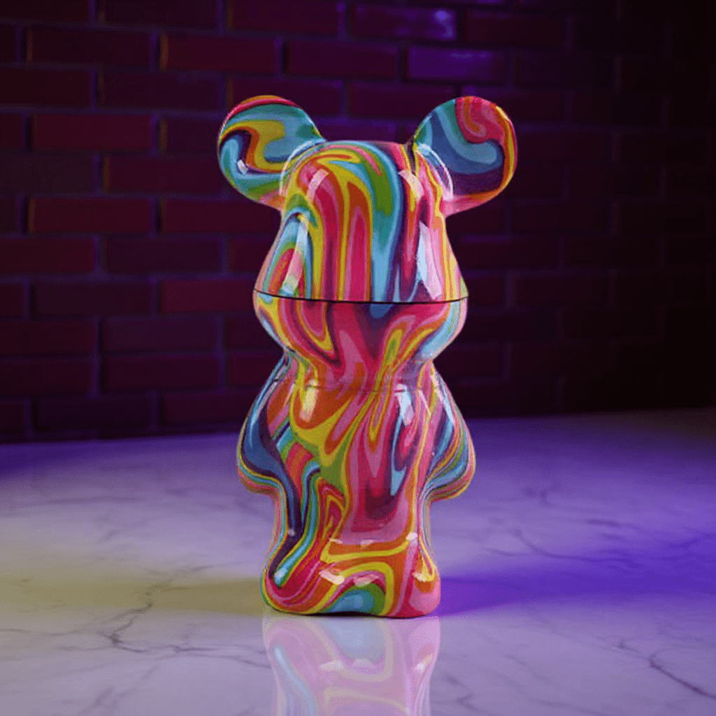 Bear Sculpture Herb Grinder - Colorful, bear - shaped grinder on a reflective surface with a dark brick wall background.
