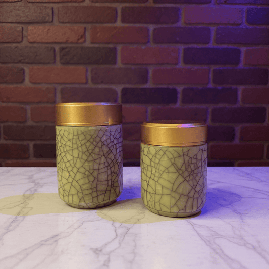 Two berge celadon porcelain stash jar with gold lids on a marble surface 