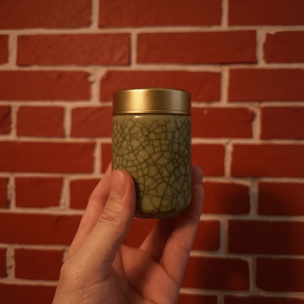 Hand holding a beige celadon porcelain stash jar with a gold lid
