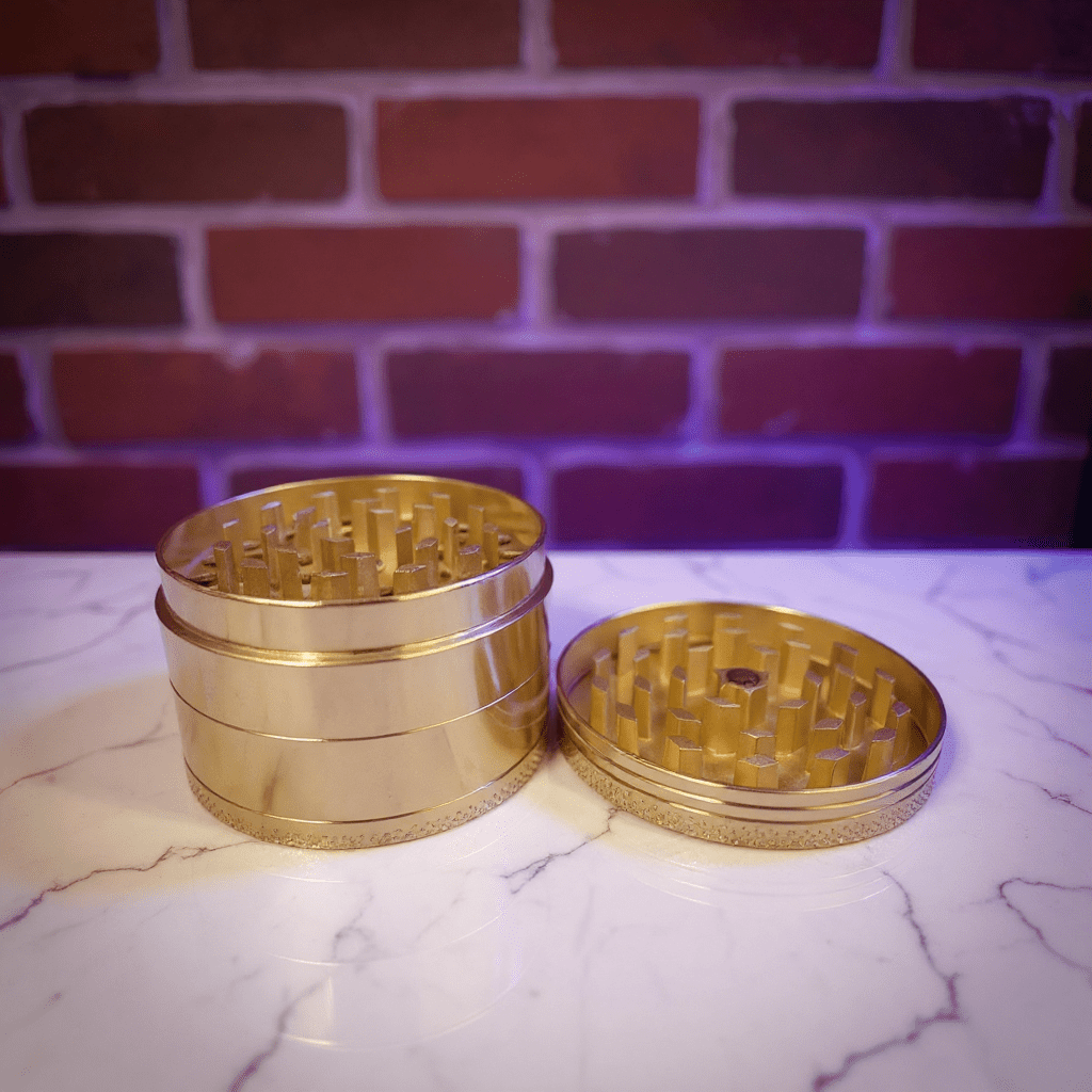 Bitcoin Herb Grinder – Gold Aluminum 4 - Piece Grinder - Gold metal grinder on a marble surface with a brick wall background