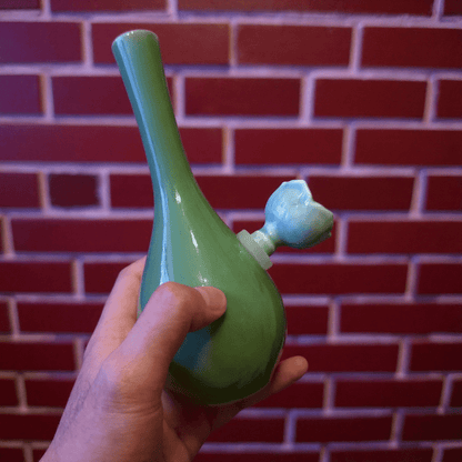 Classic Green Celadon Porcelain Bong with Slim Neck DesignGreen ceramic bong with ceramic bowl is held by hand against a brick wall background