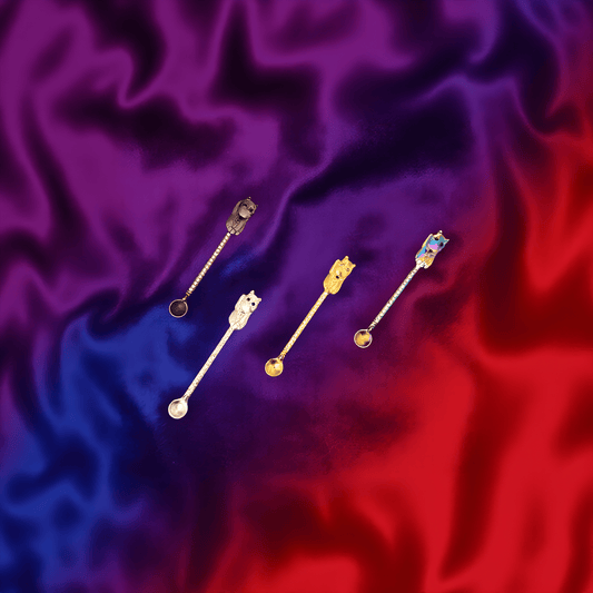 Cosmic Cat Duo Spoon Set - Overhead shot of a full set of four colorful cat - shaped herb scoops on purple - red satin.