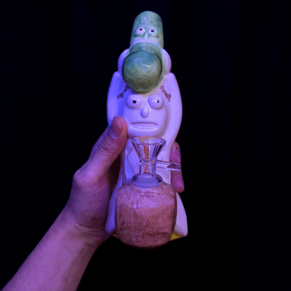 Glass pipe with character design held by a hand against a black background