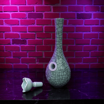 Crackle Glaze Slim Neck Celadon Porcelain Bonga green ceramic bong and a ceramic bowl is placed on a textured surface