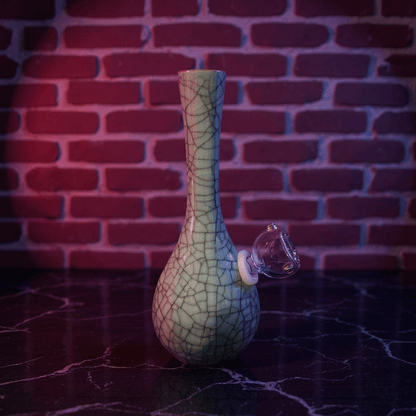 Crackle Glaze Slim Neck Celadon Porcelain Bonga slim neck crackle celadon porcelain bong with glass bowl is placed on a wooden surface.