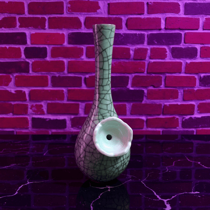 Crackle Glaze Slim Neck Celadon Porcelain BongGreen ceramic bong with a textured surface against a brick wall.