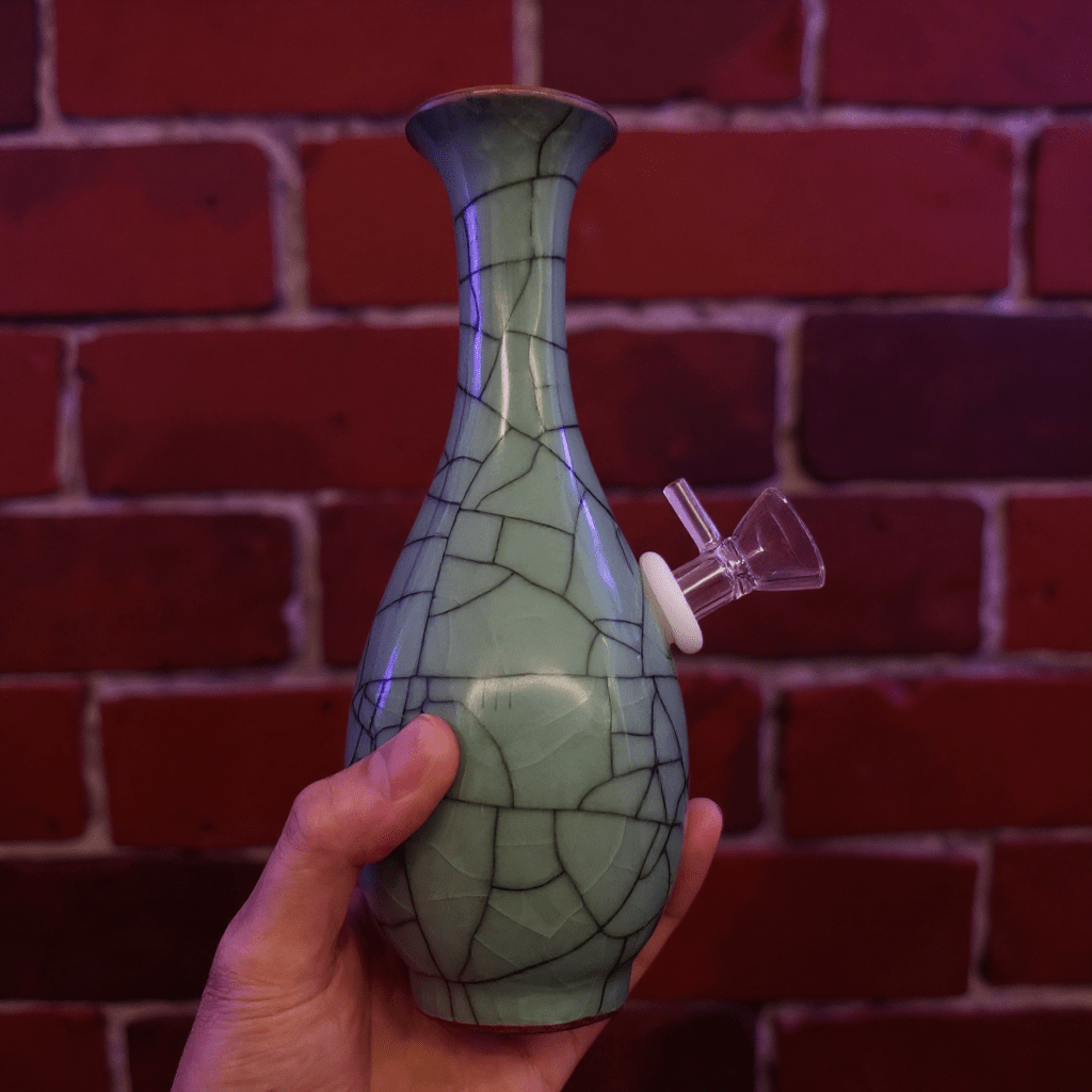 Crackled Light Green Celadon Porcelain Bong – Elegant Ceramic BongHand holding a green ceramic bong with a textured pattern