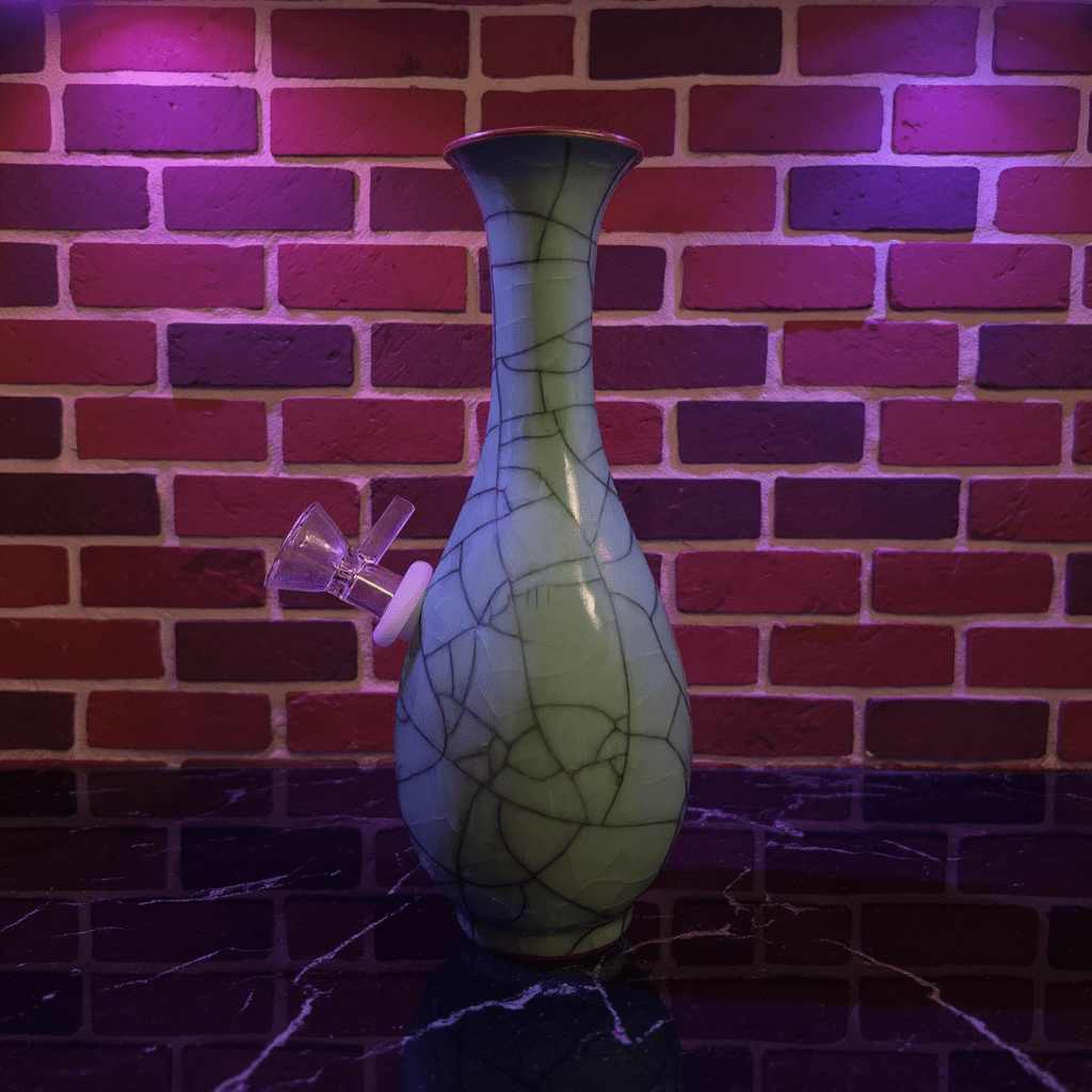 Crackled Light Green Celadon Porcelain Bong – Elegant Ceramic BongDecorative porcelain bong with a unique pattern against a brick wall background