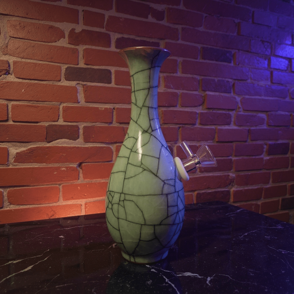 Crackled Light Green Celadon Porcelain Bong – Elegant Ceramic BongDecorative porcelain bong with a cracked glass design against a brick wall.