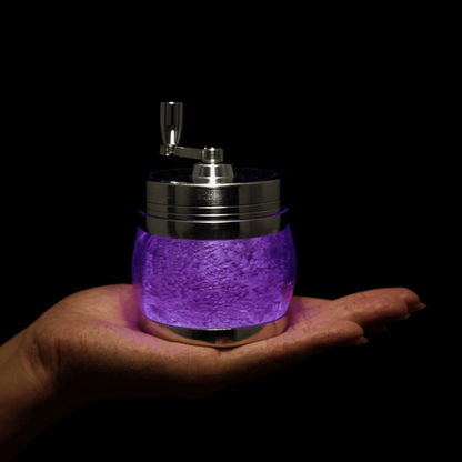 Crystal Hand Crank Herb Grinder - Close - up of a hand cradling a luxurious purple stone grinder with steel trim.