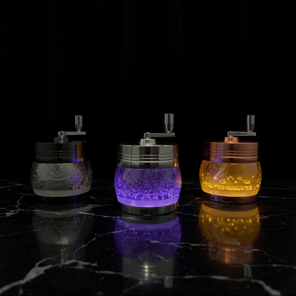 Crystal Hand Crank Herb Grinder - Three designer grinders in purple, bronze, and amber displayed on a bed.