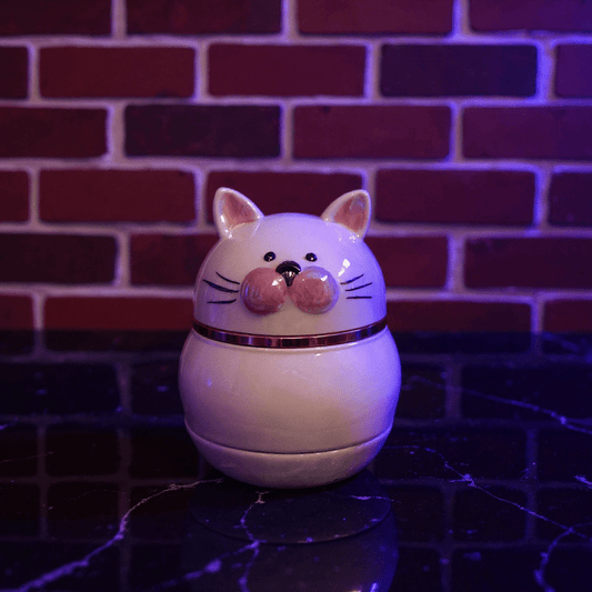 Cute Ceramic Cat Herb Grinder – Spice CrusherCat - shaped ceramic herb grinder on a reflective surface with a brick wall background