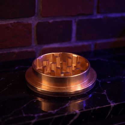 Cute Ceramic Dog Herb GrinderBronze - colored metal grinder on a dark surface with a brick wall background