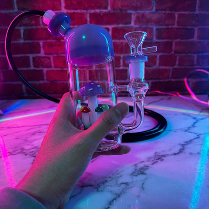 Cute Mushroom Percolator Bong – Mini Fairycore Glass BubblerGlass smoking bong held by a hand with a brick wall background