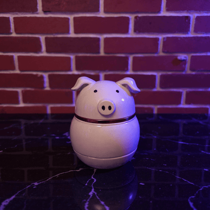 Cute Pig Ceramic Herb Grinder – Spice Crusher- White pig shaped ceramic grinder on a dark surface with a brick wall