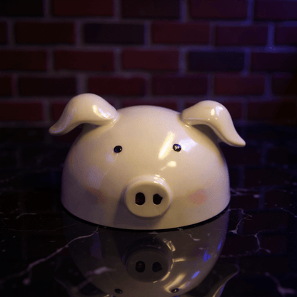 Cute Pig Ceramic Herb Grinder – Spice Crusher- White pig shaped grinder head on a reflective surface with a brick wall