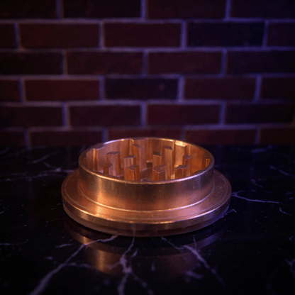 Cute Pig Ceramic Herb Grinder – Spice Crusher - Bronze colored metal grinder on a dark surface with a brick wall
