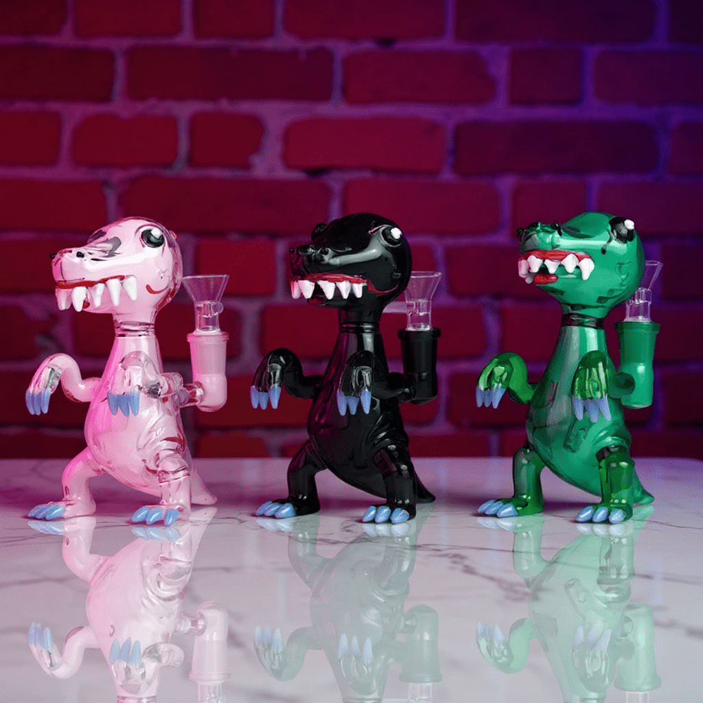 DinoRex Glass Bong - Borosilicate Glass DragonThree colorful dinosaur - like glass bongs with pan against a brick wall background.