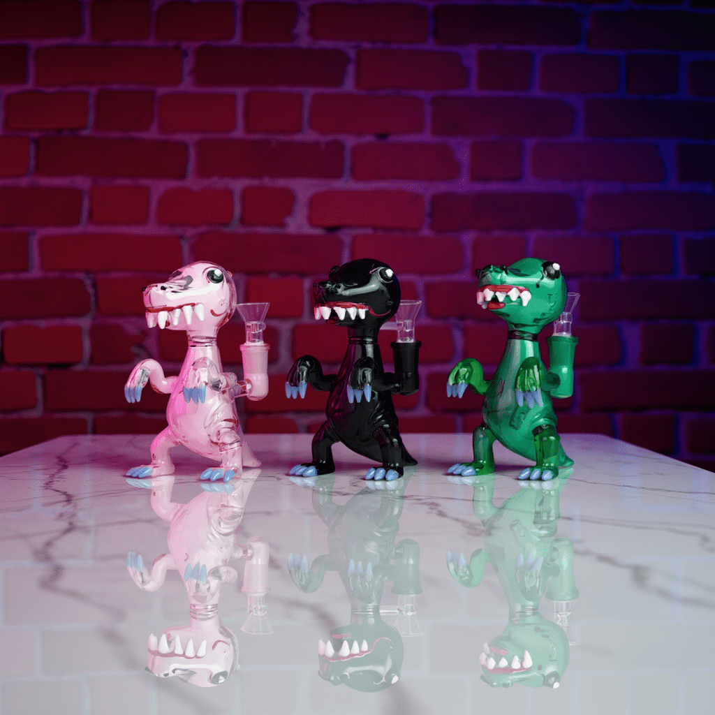 DinoRex Glass Bong - Borosilicate Glass DragonDinoRex Water Pipe - Three dinosaur - shaped glass bongs in pink, gray, and green lined up on smoky floor